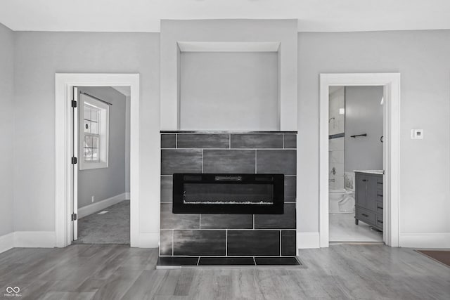 interior details with wood-type flooring and a tile fireplace