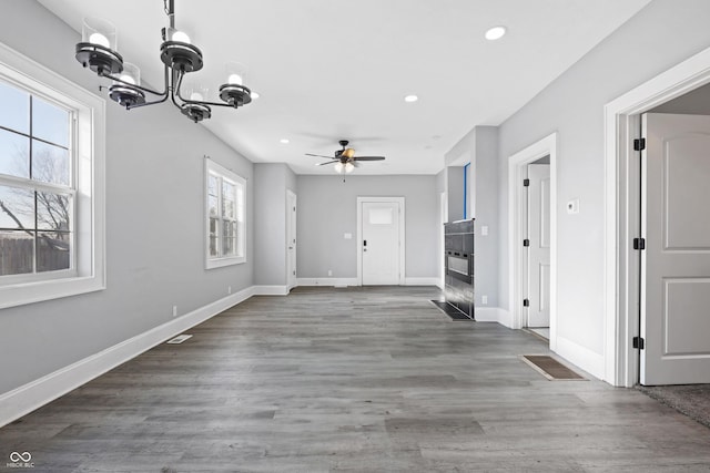 interior space featuring a wealth of natural light, ceiling fan with notable chandelier, and dark hardwood / wood-style flooring