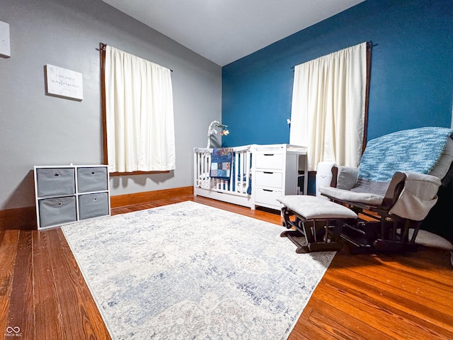 bedroom with a crib and hardwood / wood-style flooring