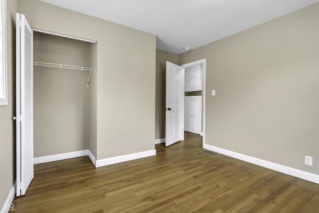 unfurnished bedroom with a closet and dark hardwood / wood-style floors