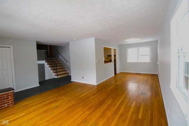 unfurnished living room with a brick fireplace, hardwood / wood-style floors, and a textured ceiling