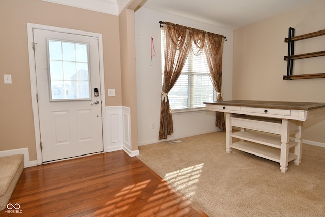 carpeted foyer with ornamental molding