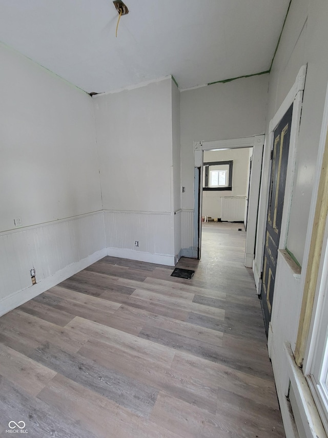 unfurnished room featuring radiator heating unit and light hardwood / wood-style floors