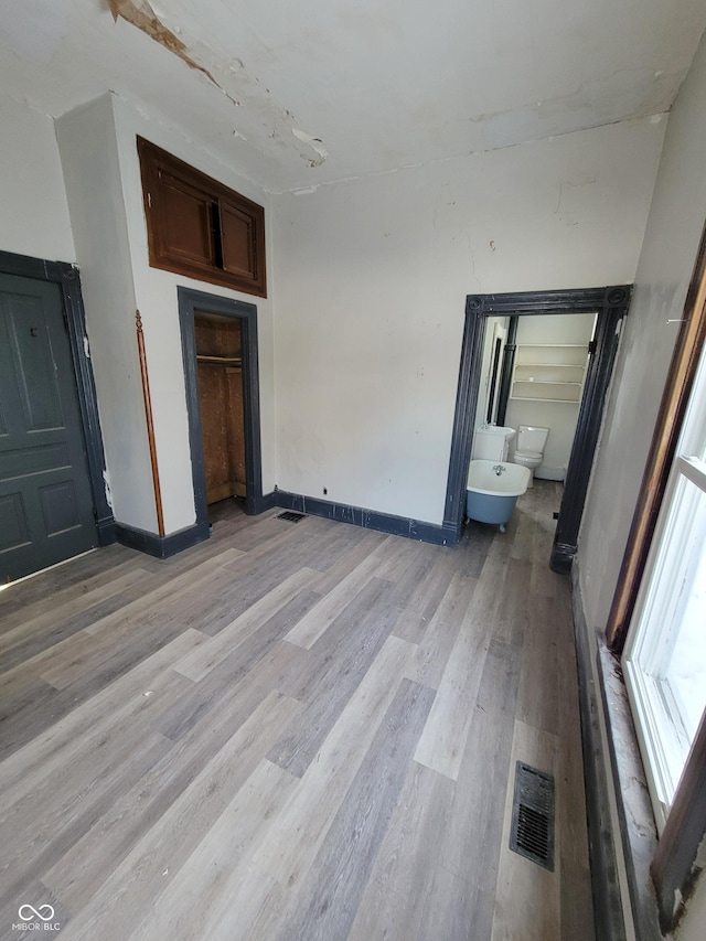 unfurnished bedroom with ensuite bathroom and light hardwood / wood-style floors