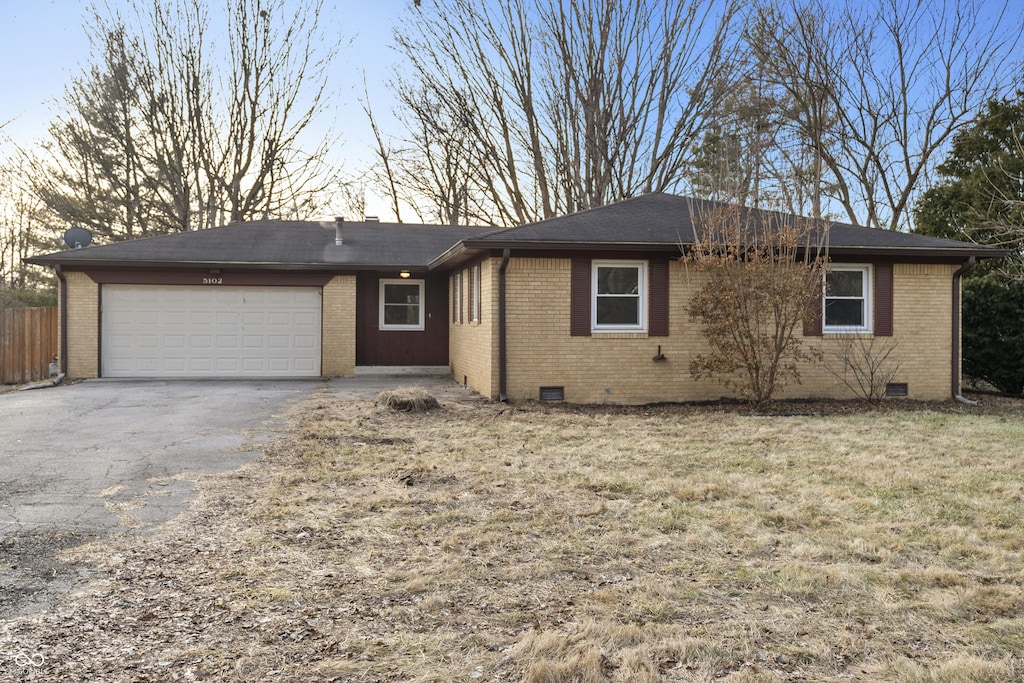 ranch-style home featuring a garage and a yard