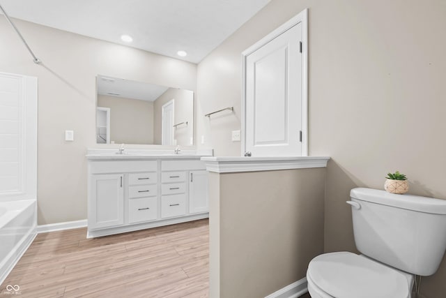 bathroom featuring wood-type flooring, toilet, and vanity