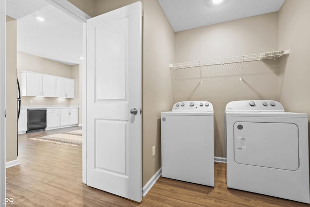 clothes washing area featuring separate washer and dryer and light hardwood / wood-style flooring