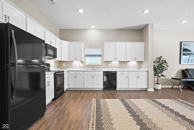 kitchen featuring dark hardwood / wood-style floors, sink, white cabinets, and black appliances