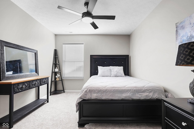 bedroom with ceiling fan, light colored carpet, and a textured ceiling