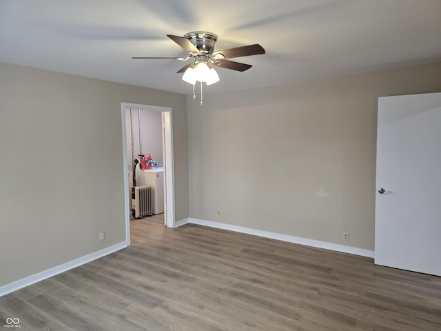 unfurnished room featuring ceiling fan, light wood-type flooring, radiator heating unit, and washer / dryer