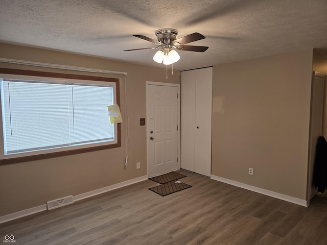 entryway with ceiling fan, a textured ceiling, and dark hardwood / wood-style floors