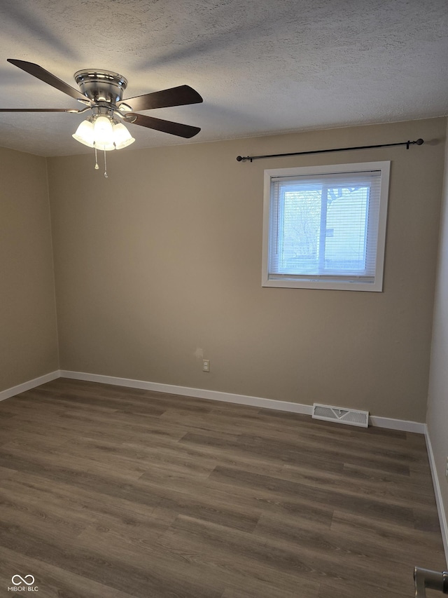 empty room featuring ceiling fan, a textured ceiling, and dark hardwood / wood-style floors