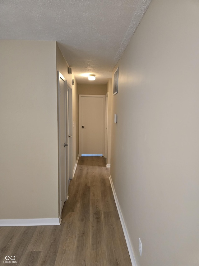 corridor with dark hardwood / wood-style floors and a textured ceiling