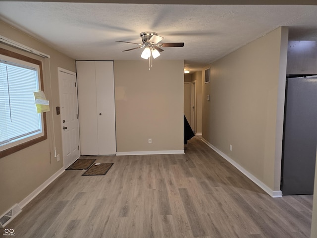 interior space featuring light wood-type flooring, ceiling fan, and a textured ceiling