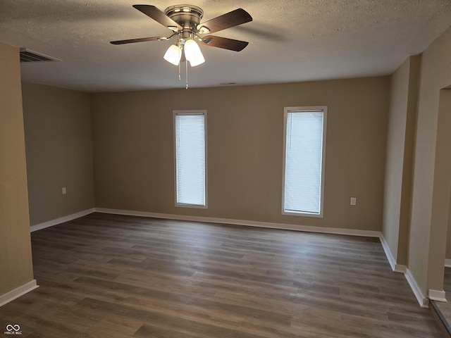 empty room featuring dark wood-type flooring, ceiling fan, and a healthy amount of sunlight