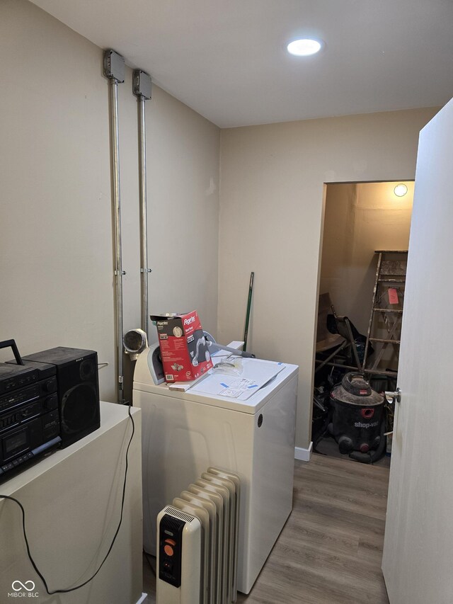 clothes washing area with light wood-type flooring, washer and clothes dryer, and radiator heating unit