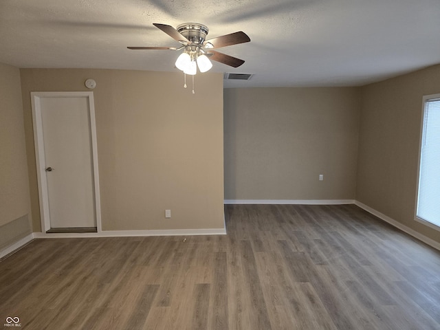 spare room featuring ceiling fan, a wealth of natural light, a textured ceiling, and hardwood / wood-style flooring