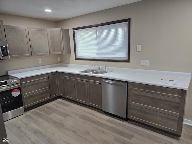 kitchen featuring dark brown cabinetry, sink, stainless steel appliances, and light wood-type flooring