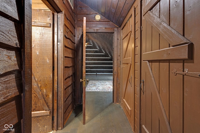 hall with lofted ceiling, wood ceiling, and wood walls