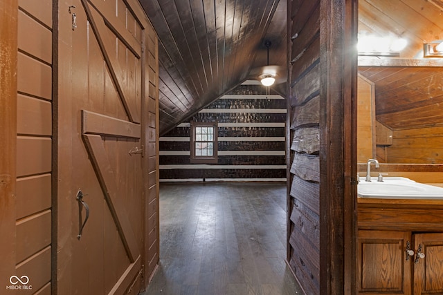 bonus room with sink, dark wood-type flooring, wooden ceiling, and wooden walls