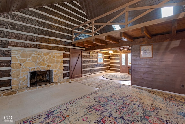 unfurnished living room with a stone fireplace, high vaulted ceiling, and wood walls