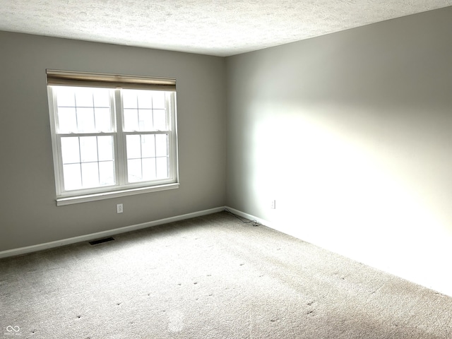 carpeted empty room featuring a textured ceiling