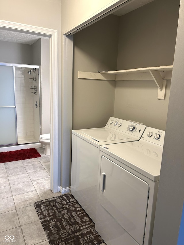 laundry area with washing machine and dryer and light tile patterned floors