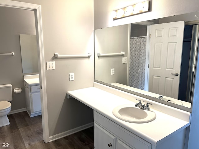 bathroom with hardwood / wood-style flooring, vanity, walk in shower, and toilet