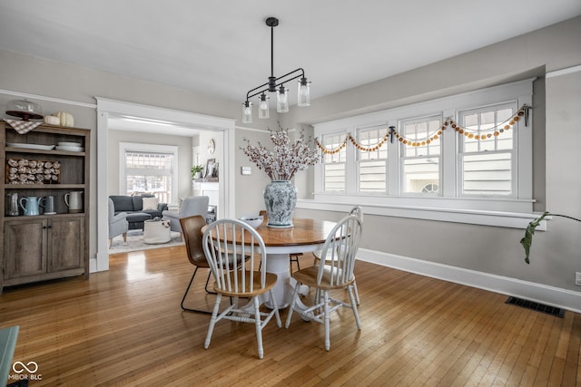 dining space with wood finished floors, visible vents, and baseboards