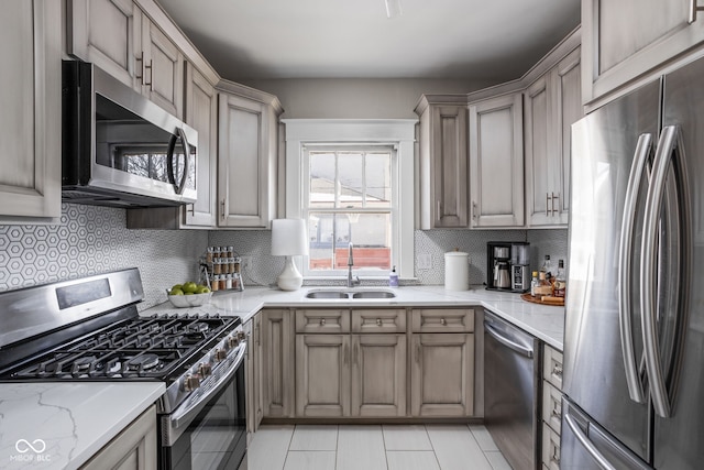 kitchen featuring stainless steel appliances, tasteful backsplash, a sink, and light stone countertops