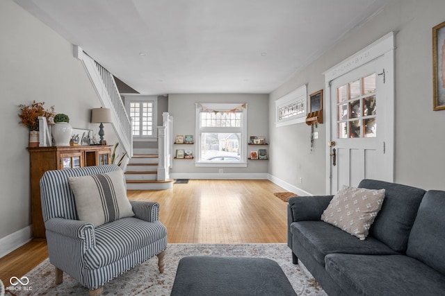 living room featuring light wood finished floors, stairway, visible vents, and baseboards