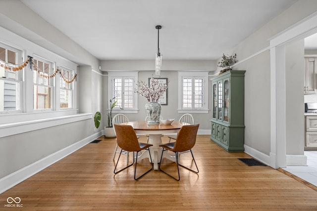 dining space featuring visible vents, light wood-style flooring, and baseboards