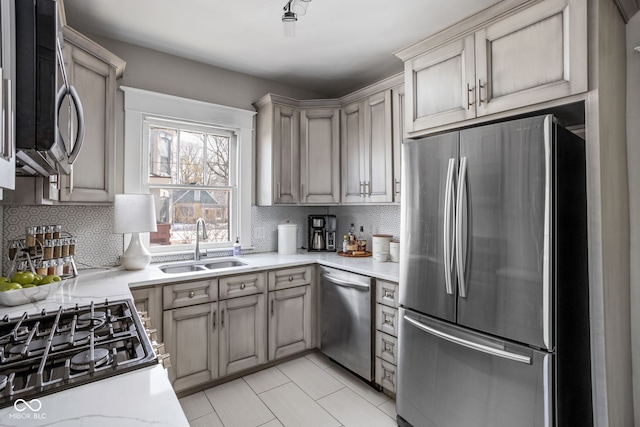 kitchen with light tile patterned floors, decorative backsplash, stainless steel appliances, light countertops, and a sink