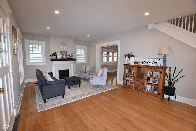 living room featuring baseboards, light wood finished floors, a fireplace, and recessed lighting