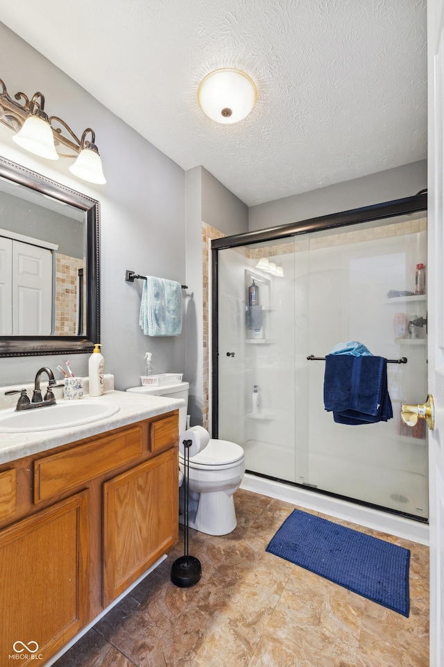 bathroom with a textured ceiling, toilet, walk in shower, and vanity