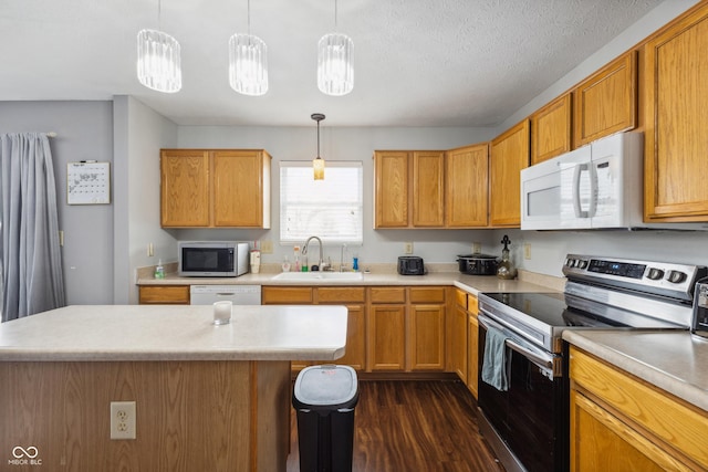 kitchen with hanging light fixtures, appliances with stainless steel finishes, sink, and a kitchen island