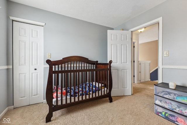 carpeted bedroom with a closet and a nursery area