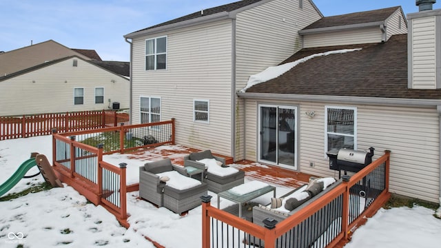 snow covered back of property with a deck