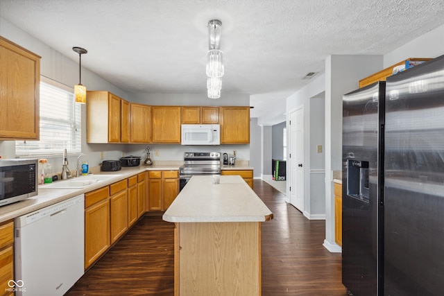 kitchen featuring decorative light fixtures, a center island, sink, appliances with stainless steel finishes, and dark hardwood / wood-style flooring