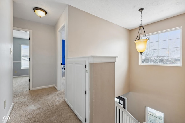 hallway featuring light colored carpet and a textured ceiling