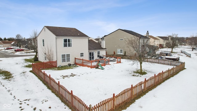 snow covered back of property with a wooden deck