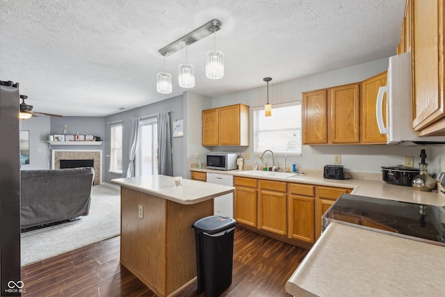 kitchen with decorative light fixtures, a kitchen island, sink, white appliances, and dark hardwood / wood-style flooring