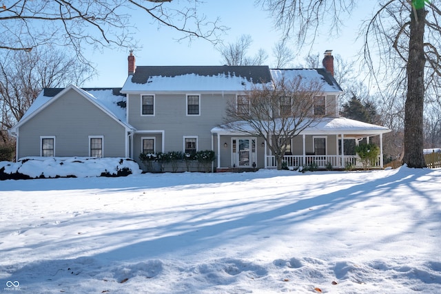 snow covered back of property featuring covered porch