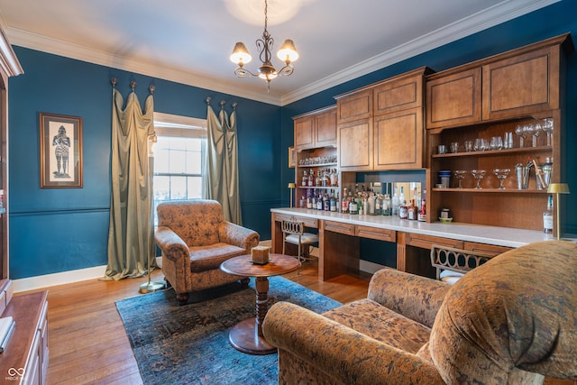 bar with light hardwood / wood-style floors, pendant lighting, ornamental molding, and a notable chandelier