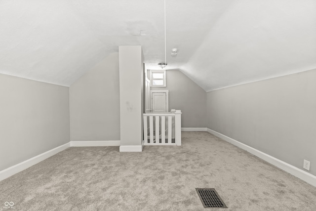 bonus room with lofted ceiling and light carpet