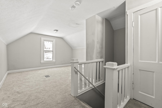 additional living space with lofted ceiling, carpet, and a textured ceiling