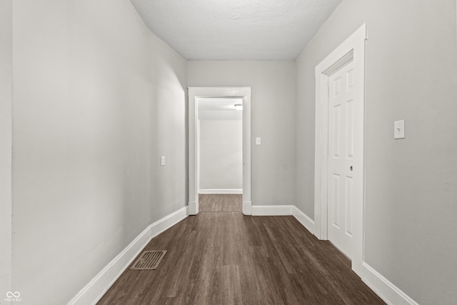 hall featuring a textured ceiling and dark hardwood / wood-style flooring