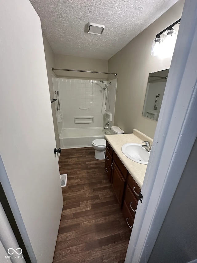 full bathroom featuring a textured ceiling, toilet, hardwood / wood-style flooring, and vanity