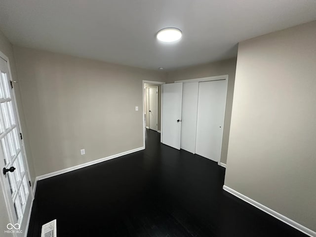 unfurnished bedroom with a closet and dark wood-type flooring