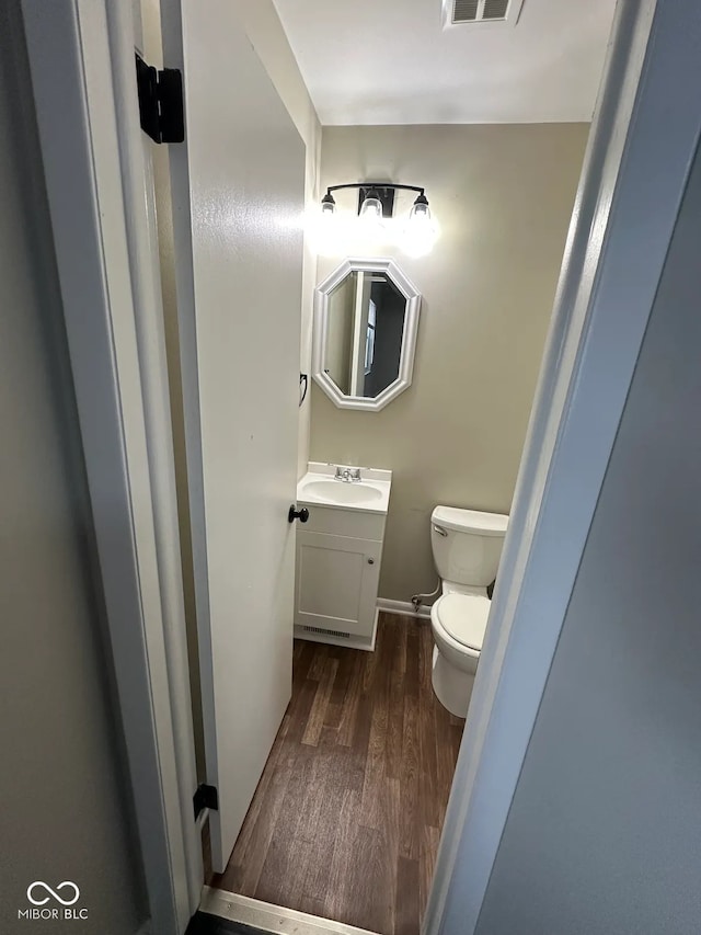 bathroom with toilet, vanity, and hardwood / wood-style floors